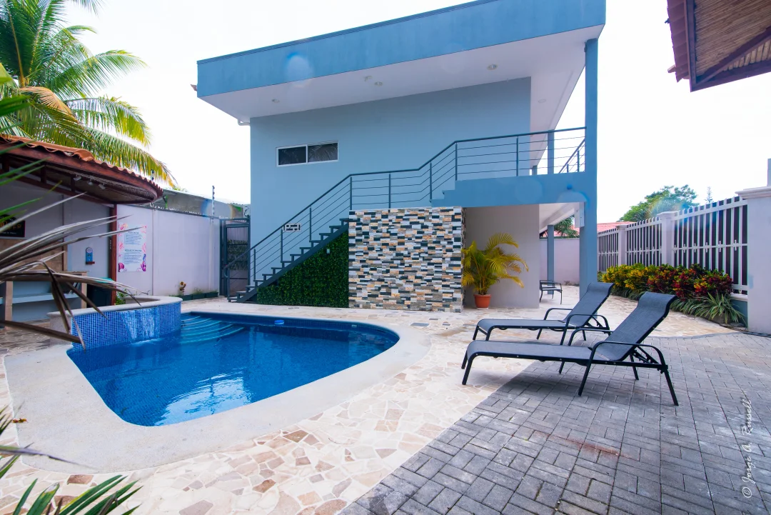 Pool and sun loungers at Corals Residences, surrounded by palms